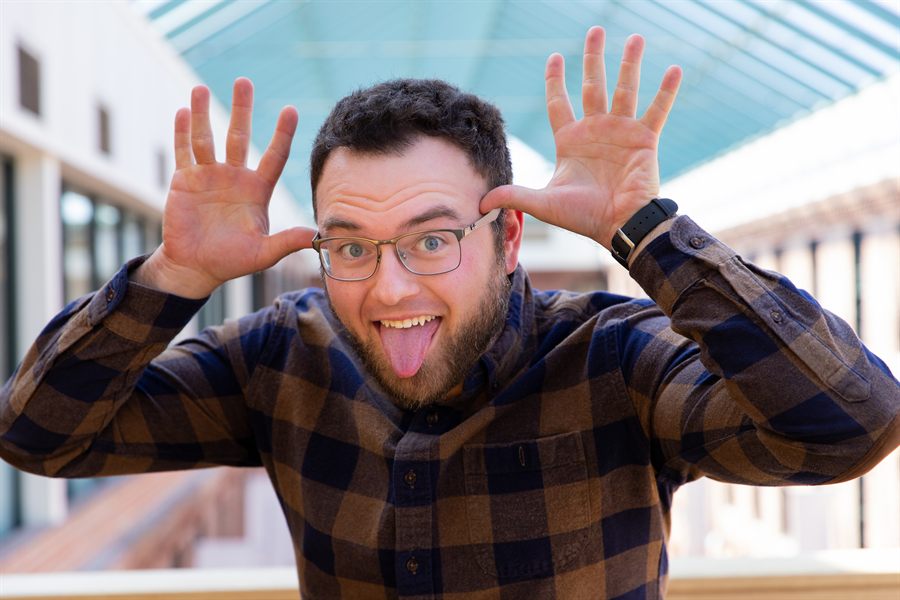 Dan Rosenbaum pulling a playful face, hands raised beside his head