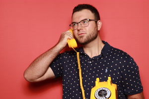 Dan Rosenbaum holding a yellow rotary phone to his ear